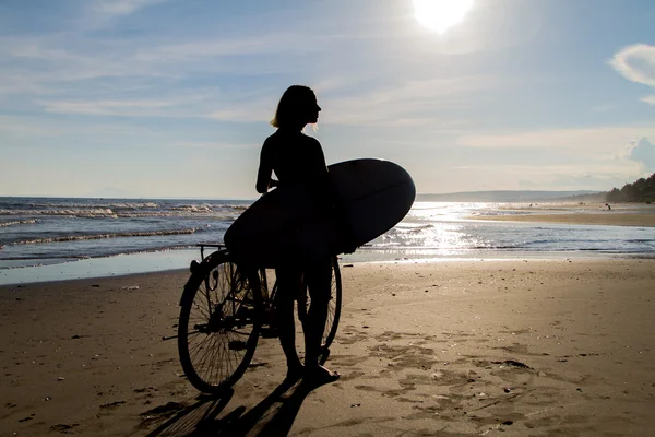 Woman on a bicycle with a surf — Stock Photo, Image