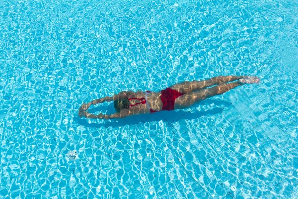 Mujer con traje de baño nadando en una piscina de agua azul —  Fotos de Stock