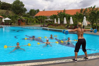 Aqua Spor salonunda aerobik fitness eğitmen bir grup insan önünde su egzersizleri yapmak.