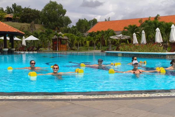 Usmívající se skupina dělá aqua aerobic v bazénu s činkami — Stock fotografie