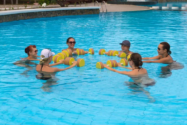 Pessoas de fitness ativas felizes fazendo exercício com haltere de aqua em uma piscina — Fotografia de Stock