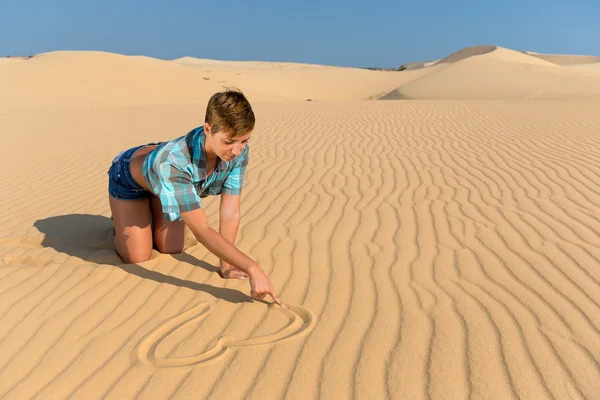 Woman sitting on beach dunes and drawing Heart on the sand — Stock Photo, Image