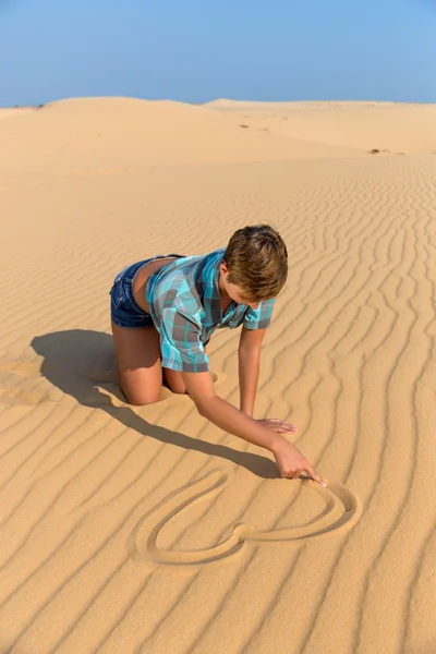 Nő ül a tengerparti dűnék és a rajz szív a homokban — Stock Fotó