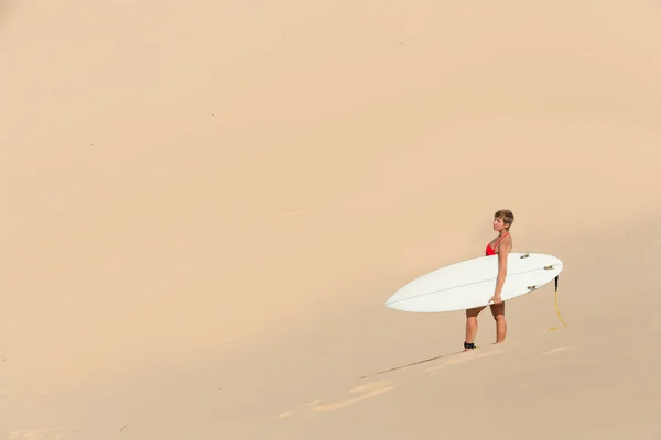 Rear view of sexy beautiful young woman surfer girl in bikini with white surfboard at a beach — Stock Photo, Image