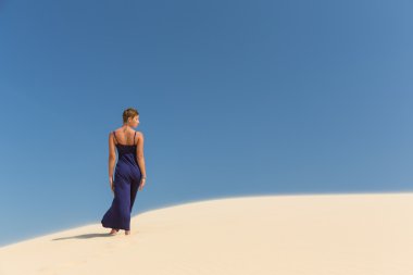 Mavi gökyüzü ve kum arka plan üzerinde elbise güzel yetişkin duygusallık kadında
