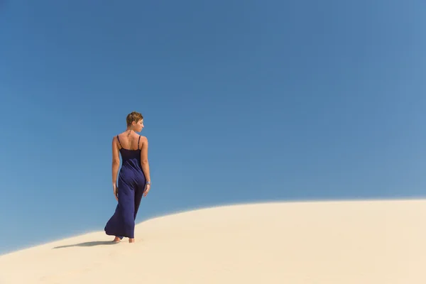 Beautiful adult sensuality woman in dress on blue sky and sand background — Stock Photo, Image