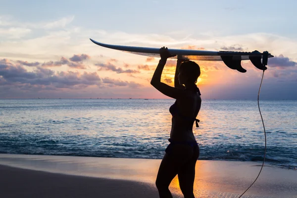 Surferin mit Surfbrett am tropischen Strand bei Sonnenuntergang — Stockfoto