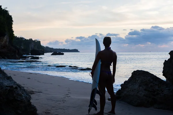 Surferin mit Surfbrett am tropischen Strand bei Sonnenuntergang — Stockfoto