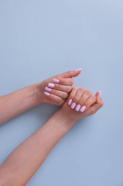 Mavi arka planda pembe manikürlü güzel kadınların elleri. Üst Manzara. Temiz cilt.