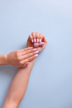 Şık moda kadın manikürü. Mavi arka planda mükemmel pembe manikürlü güzel bir kadın eli..