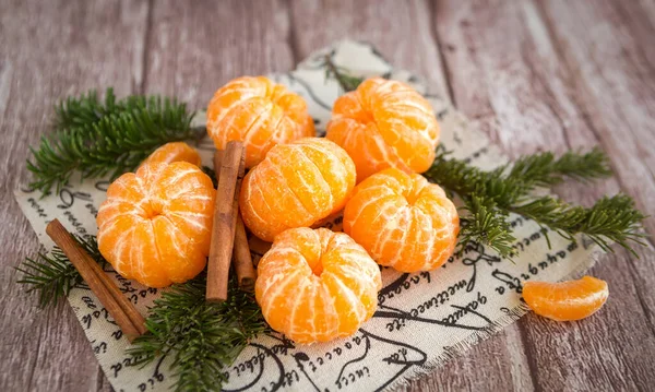 Mandarines ou mandarines orange et bâtonnets de cannelle sur branches Arbre de Noël sur fond de bois brun. — Photo