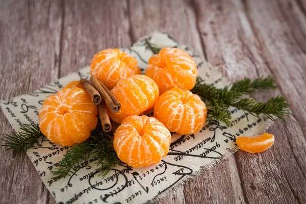 Mandarines ou mandarines et bâtonnets de cannelle sur branches Arbre de Noël sur fond de bois brun. — Photo