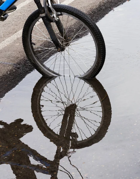 Reflection silhouette of a bike wheel with spokes in a puddle. — Zdjęcie stockowe