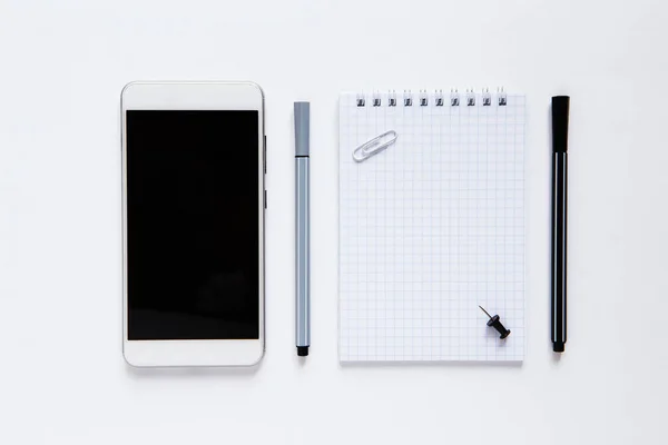 Flat lay com notebook, telefone, canetas sobre fundo branco. Escritório de negócios ou conceito de planejamento. Espaço de cópia para texto. — Fotografia de Stock