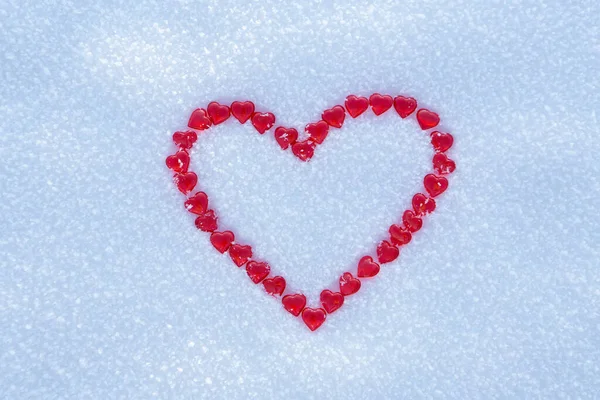 Red heart made with lots of little hearts on the center of snow background. Royalty Free Stock Images