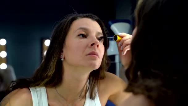 Vrouw schildert lippen met rode en roze lippenstift. Een donkerharige vrouw met een gladde huid en heldere make-up blik op spiegel — Stockvideo