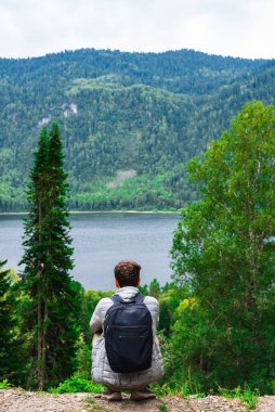 Gölün kenarında oturan ve doğanın tadını çıkaran bir adam.