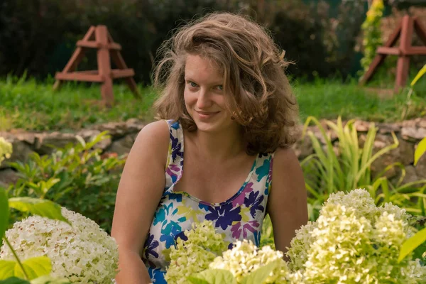 Bahçede beyaz ortanca çiçeklerinin arasında genç bir kadın