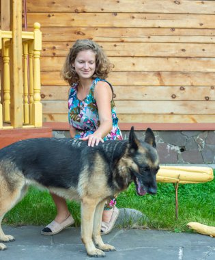 Köpeğiyle evin bahçesinde Alman çoban köpeği olan kız.