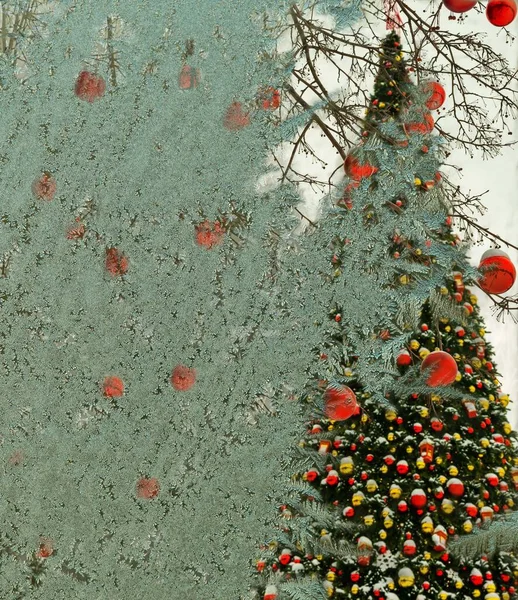 Kerstboom met rode ballen door een bevroren raam — Stockfoto