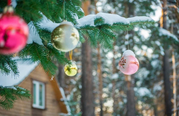 Árbol de abeto con juguetes de Navidad frente a una casa de madera — Foto de Stock