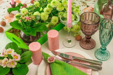 Şarap bardakları, mumlar ve çiçeklerle romantik bahar sofrası.