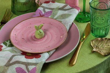 Yemek odasında süslemeleri olan güzel yuvarlak masa. Tavşan figürü, cam eşyalar, söğüt dalları.