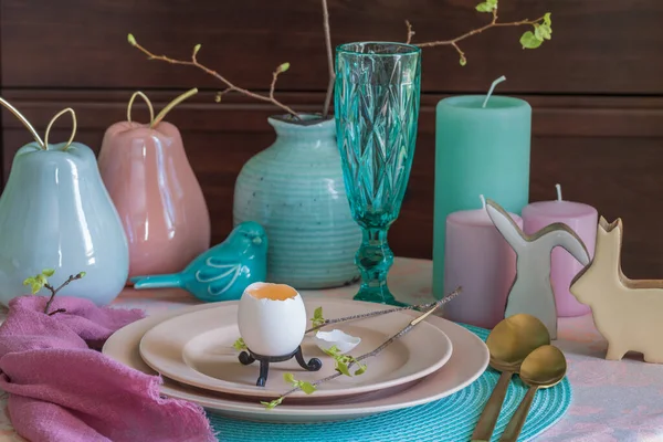 Spring table set for Easter - a chicken egg and a twig with the first leaves on a plate — Stock Photo, Image