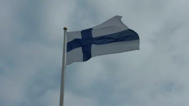 Finnish flag blowing in the wind with rain clouds in the background