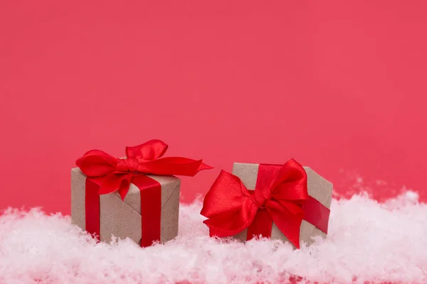 雪とピンクの背景に贈り物とクリスマスボックス 年賀状のミニマルな様式 ロイヤリティフリーのストック画像