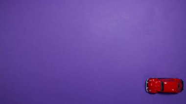 Kırmızı bir oyuncak araba mor bir arka planda gider. Hareketi durdur.