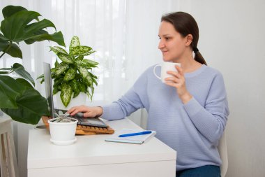 Siyah saçlı mutlu kız evde dizüstü bilgisayarla çalışıyor. Uzaklık eğitimi ve çalışma.