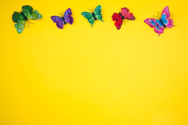 Parlak sarı arka planda dekoratif kelebekler. Bahar-yaz sezonu konsepti.