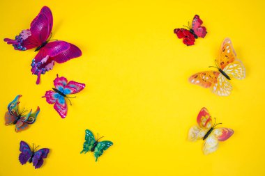 Parlak sarı arka planda dekoratif kelebekler. Bahar-yaz sezonu konsepti.