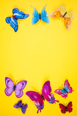 Parlak sarı arka planda dekoratif kelebekler. Bahar-yaz sezonu konsepti.