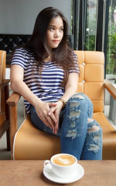 Asyalı kadın cappuccino kahve ile pencereden dışarı bakarak woo