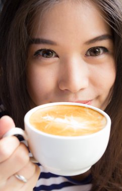 gülümseyen ve cappuccino kahve tutan kadının yakın çekim