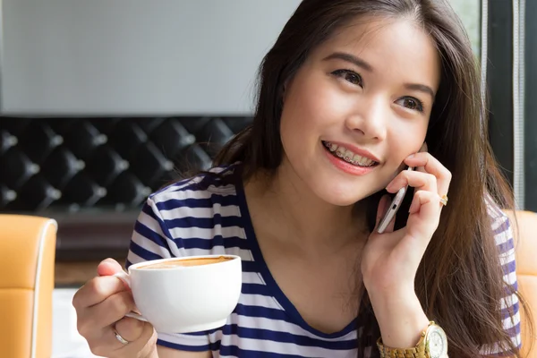 Hermosa mujer hablando por teléfono y sosteniendo una taza de café — Foto de Stock