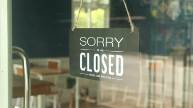 Adam kapalı tabelasını cam kapıya açık tabelayla değiştiriyor.