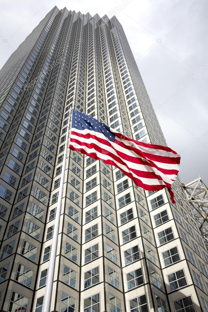 US flag waving against building and grey sky