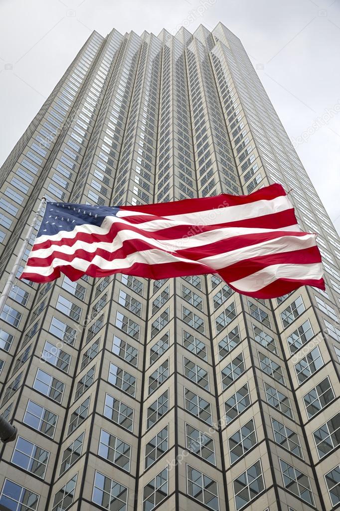 US flag waving against building and grey sky