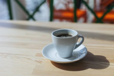 Kafedeki ahşap bir masada bir fincan sade kahve. Metin için yer.