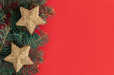 Kırmızı arka planda altın parıldayan yıldızlar ve ladin dalları. Düz yatıyordu. Metin için yer.