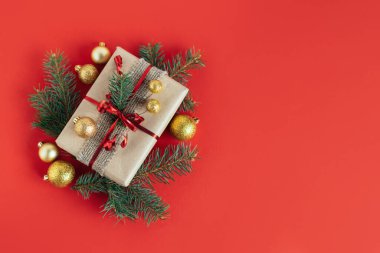 Ladin dallı bir hediye kutusu ve kırmızı arka planda noel süsleri. Tatil konsepti. Mesaj için yer. Düz yatıyordu.