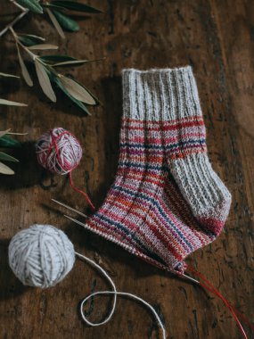 İğneli el örgüsü çorap ve koyu ahşap arka planda gri iplik topu. El yapımı ve yavaş yaşam için higge kavramı.