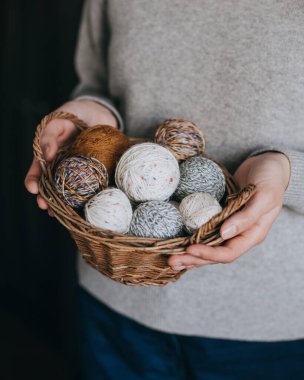 Örgü örmek için elinde yün yumağı olan bir sepet tutan kadın. Seçici odak.