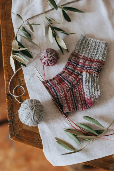 İğneli el örgüsü çorap ve koyu ahşap arka planda gri iplik topu. El yapımı ve yavaş yaşam için higge kavramı.
