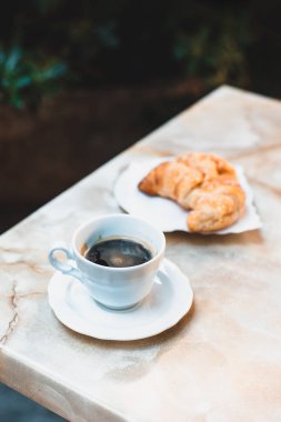 Kahvaltı için bir fincan kahve ve kruvasan bir kafede masanın üzerinde. Seçici odaklanma. Metin için yer.