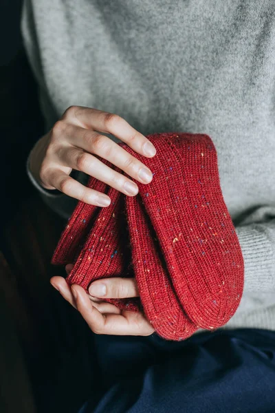 Female hands with red hand knitted socks. Selective focus.