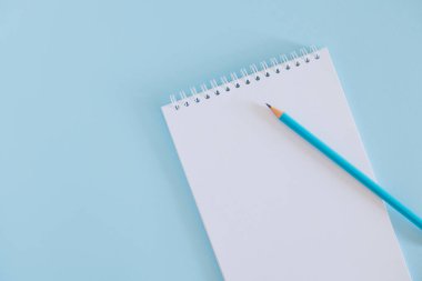 Notebook with blank page and pencil on light blue background. Flat lay. Place for text.